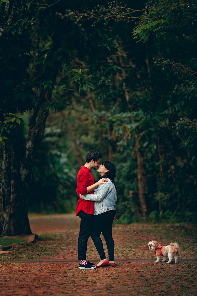 Young couple embracing in a lush forest with their small dog. A moment of affection and togetherness.