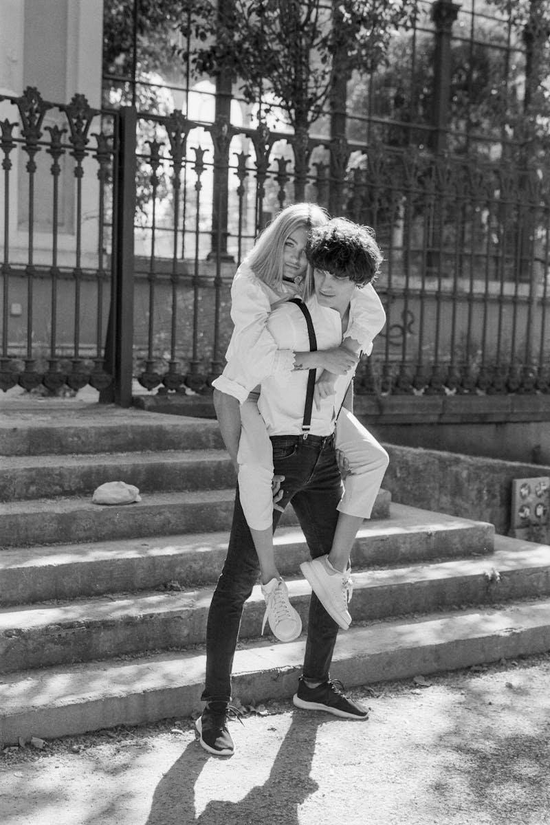 Monochrome photo of a joyful couple enjoying a piggyback ride in the city.