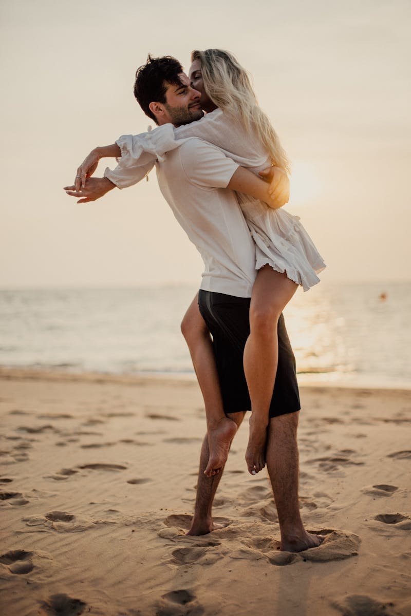 Happy couple embracing on sandy beach at sunset, enjoying vacation romance.