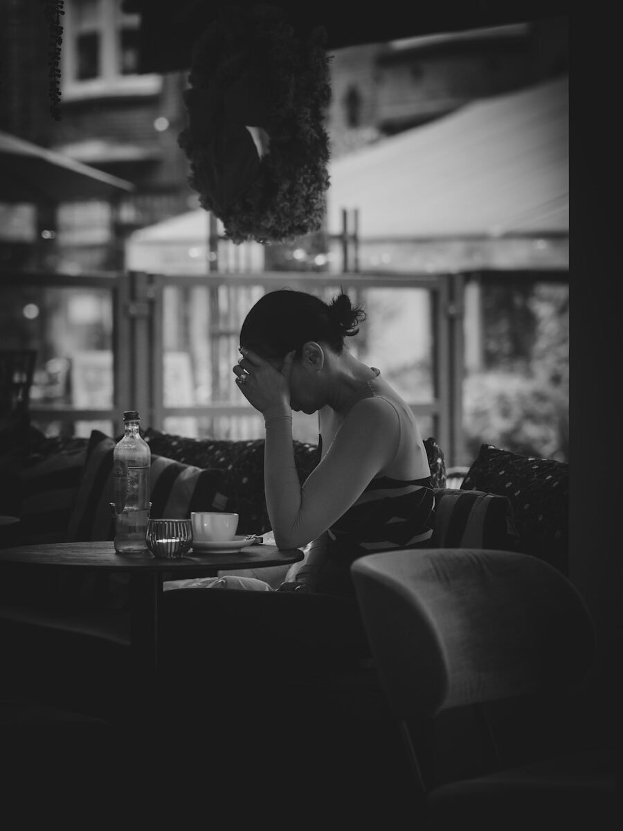 Woman sitting at a table with her head in hands.